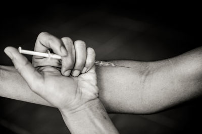 Close-up of person taking drug through syringe 