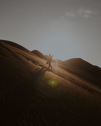 Low angle view of people on sand at desert against sky