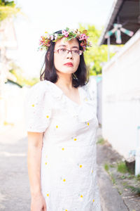 Portrait of young woman standing against wall