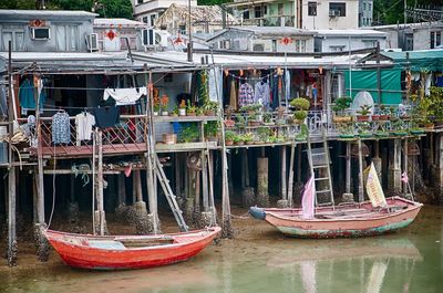 Boats moored on riverbank against stilt houses
