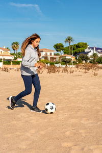 Full length of boy playing soccer on beach