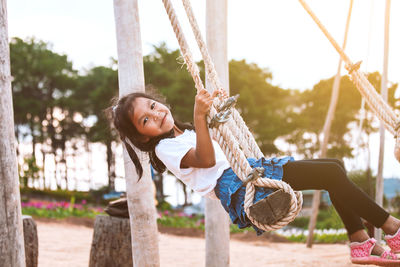 Full length side view of girl swinging at playground