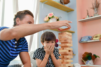 Father and son playing with block toys while sitting on floor at home