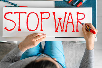 Man writing anti-war banner at home