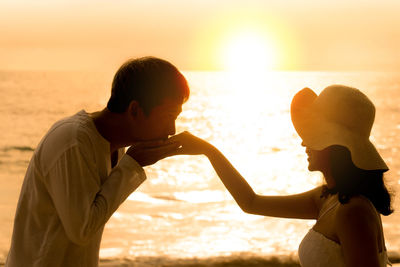 Side view of father and son at beach during sunset