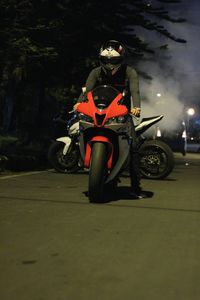 Man riding motorcycle on street at night