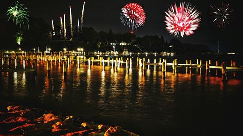 Firework display over lake against sky at night