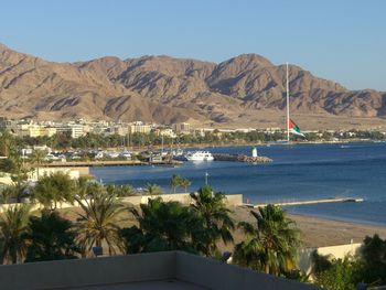 Scenic view of sea by mountains against clear sky