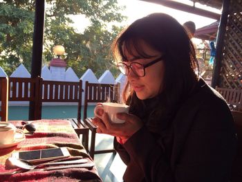 Young woman drinking tea while sitting at table in morning