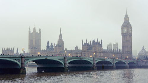 Bridge over river in city against sky