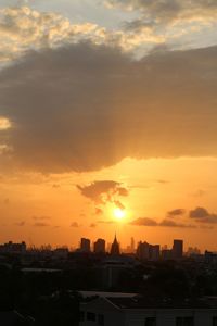 Cityscape against dramatic sky during sunset