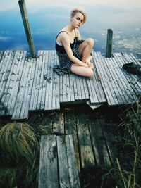 Full length of woman sitting on wooden pier