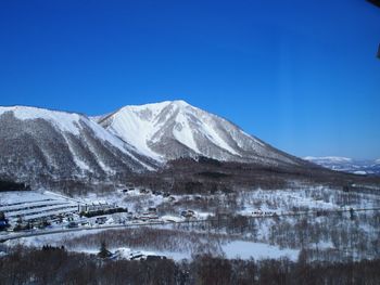 Scenic view of snow covered mountains against blue sky