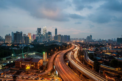 High angle view of illuminated street amidst buildings against sky