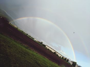 Scenic view of rainbow over land against sky