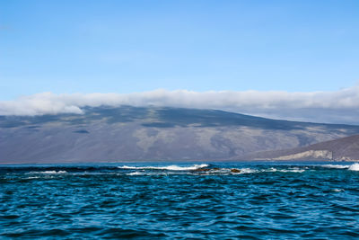 Scenic view of sea and mountains against blue sky