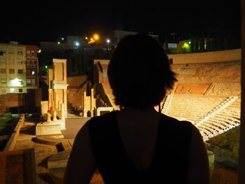 Rear view of woman sitting at illuminated night