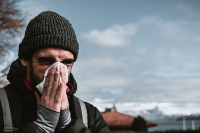 Close-up of man blowing nose with tissue paper