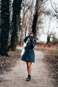 Full length of woman photographing in forest