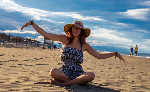 Full length of woman sitting on beach against sky
