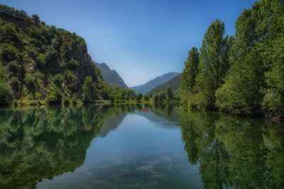 Scenic view of lake by trees against blue sky