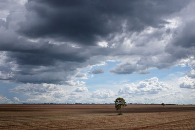 Storm clouds over landscape against cloudy sky
