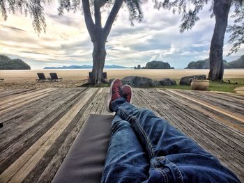 Low section of man lying on deck at beach