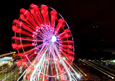 Illuminated ferris wheel against sky at night
