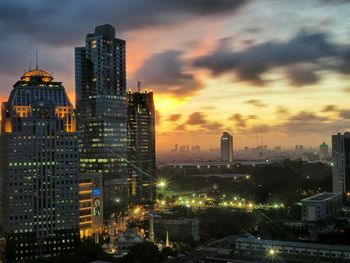 Illuminated cityscape against sky at dusk