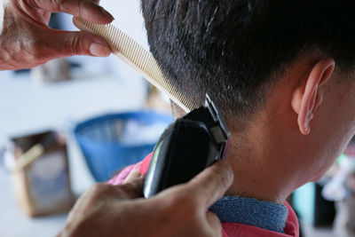 Closeup rear view head of man having a hair cut with battalion and comb