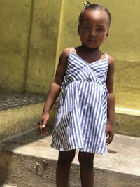 Portrait of young woman standing against wall