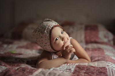 Toddler baby girl in bonnet lying on a blanket in the bedroom. real interior and natural fabrics