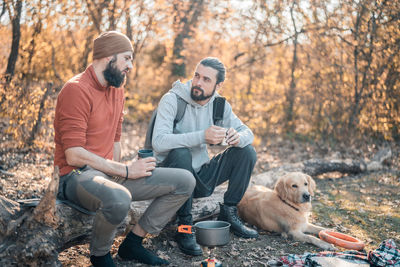 Men sitting with dog on sidewalk during autumn