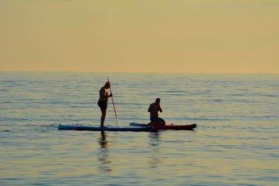 Men on paddleboards during sunset