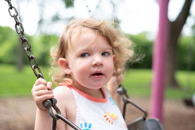 Cute girl looking away while sitting on swing 