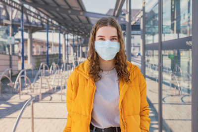 Portrait of teenage girl wearing mask standing outdoors