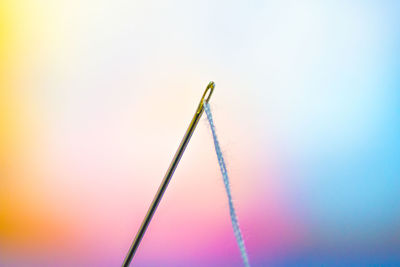 Close-up of needle and thread against colorful background