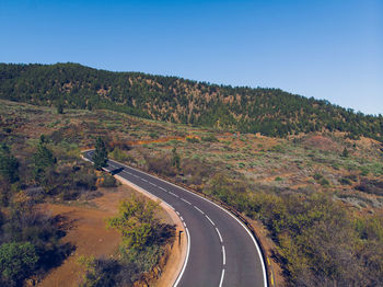 Road leading towards mountains against clear sky