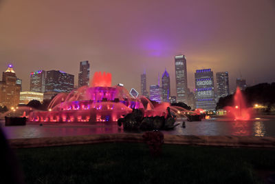 Illuminated buildings in city against sky at night