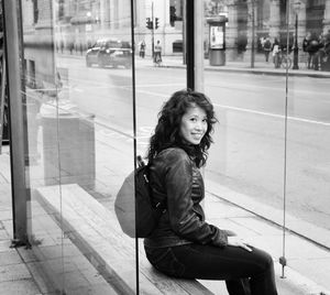 Portrait of woman sitting on glass window