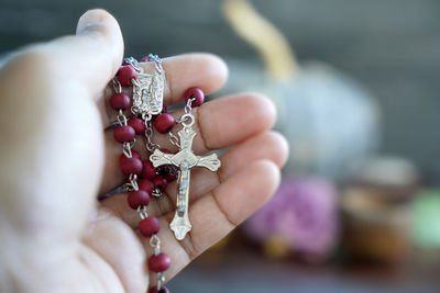 Close-up of hand holding red rosary. praying rosary concept.