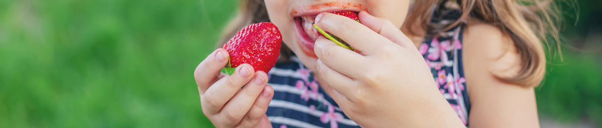 Midsection of girl eating strawberry