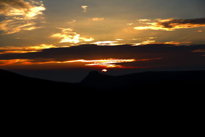 Silhouette of landscape against cloudy sky