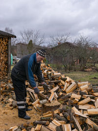 Side view of man sitting on wooden logs