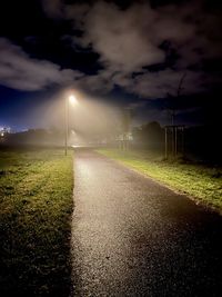 Road amidst field against sky during sunrise