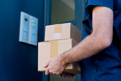Midsection of man holding parcel against wall