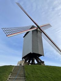 Low angle view of traditional windmill on field against sky