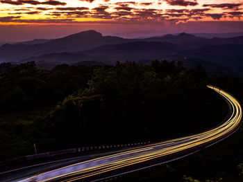 Light trails on road against sky at sunset