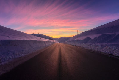 Empty road against sky during sunset