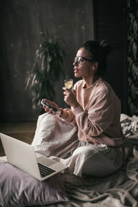 Young woman using mobile phone while sitting at home